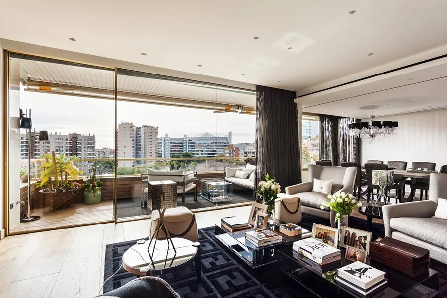 Salon moderne avec vue sur des immeubles à travers de grandes baies vitrées.
