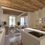 Cuisine moderne ouverte sur salon avec plafond en bois et carrelage décoratif.