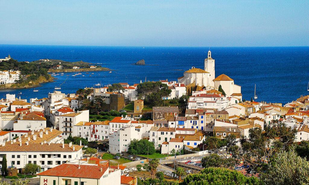 Vue de Cadaqués avec maisons blanches et église près de la mer.