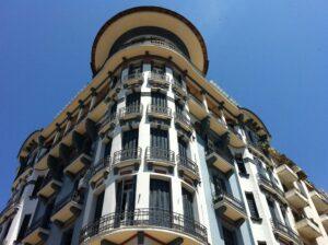 Immeuble ancien avec balcons en fer forgé sous un ciel bleu.
