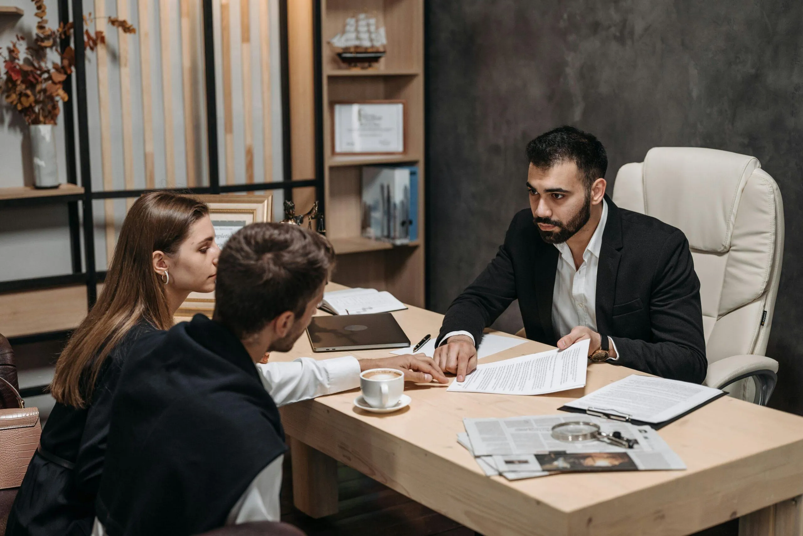 Un homme en costume discute avec un couple dans un bureau.