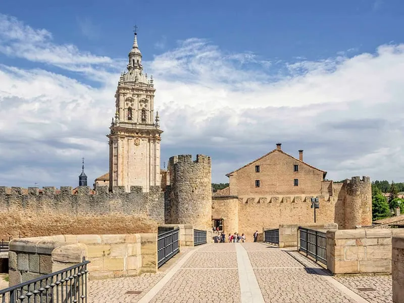 Forteresse médiévale avec tour et remparts sous un ciel bleu.